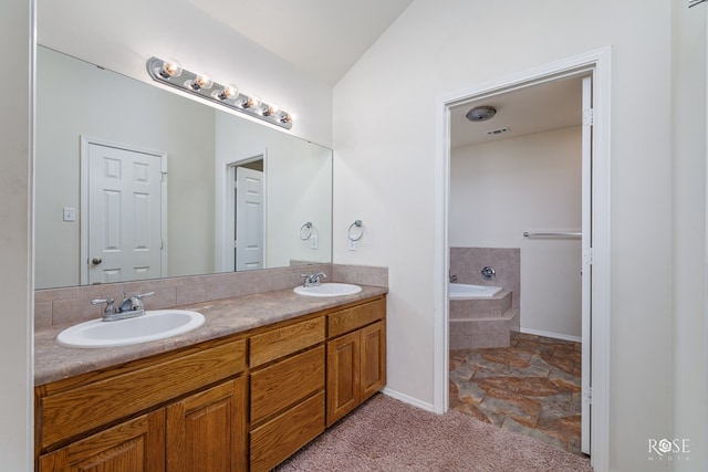 bathroom featuring tiled tub, vanity, and vaulted ceiling