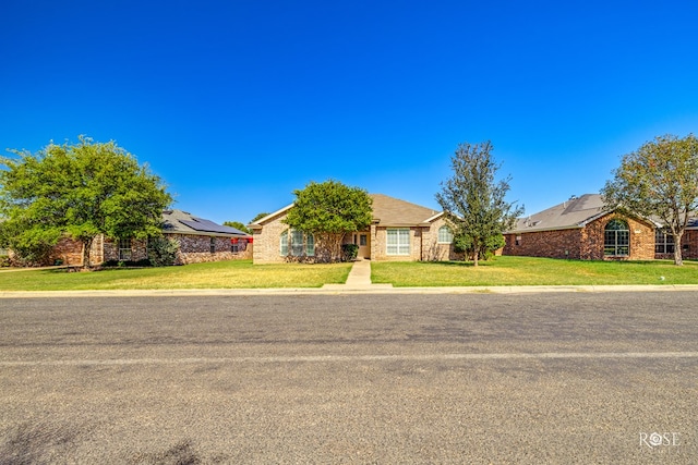 ranch-style house with a front yard and solar panels