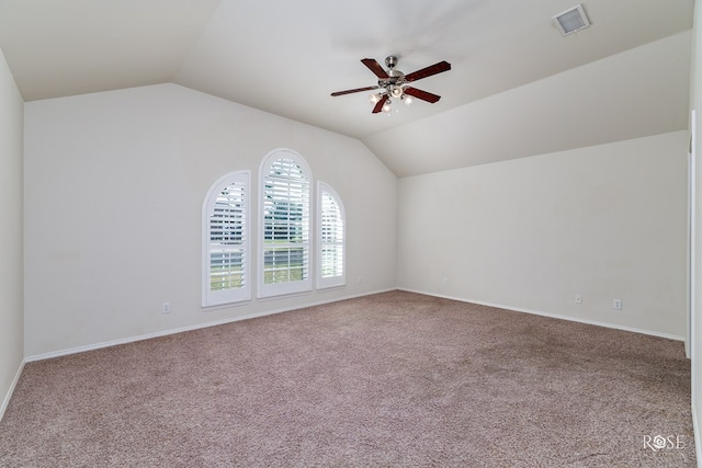 carpeted spare room featuring vaulted ceiling and ceiling fan