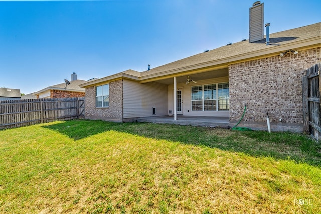 rear view of house featuring ceiling fan, a yard, and a patio