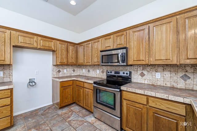 kitchen with stainless steel appliances, tile countertops, and backsplash