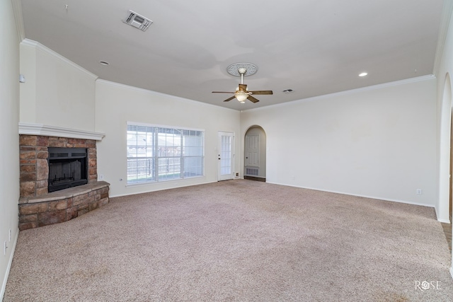 unfurnished living room featuring crown molding, a stone fireplace, carpet flooring, and ceiling fan