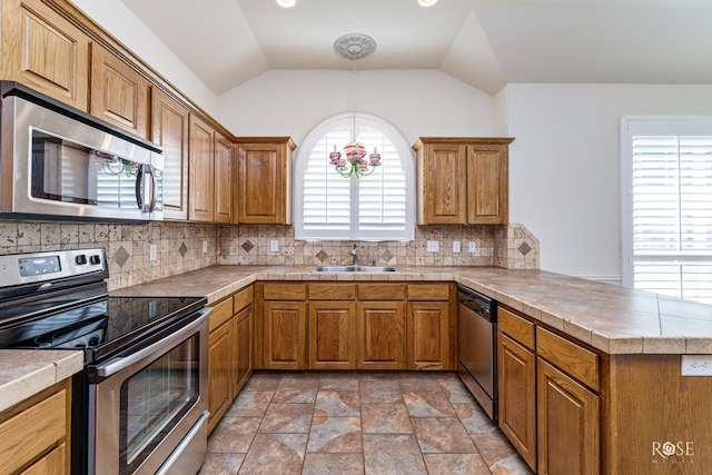 kitchen featuring sink, tasteful backsplash, hanging light fixtures, kitchen peninsula, and stainless steel appliances