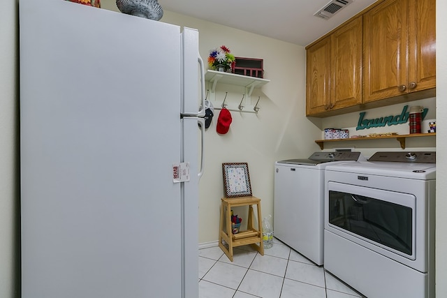 laundry area featuring cabinets, washing machine and dryer, and light tile patterned flooring