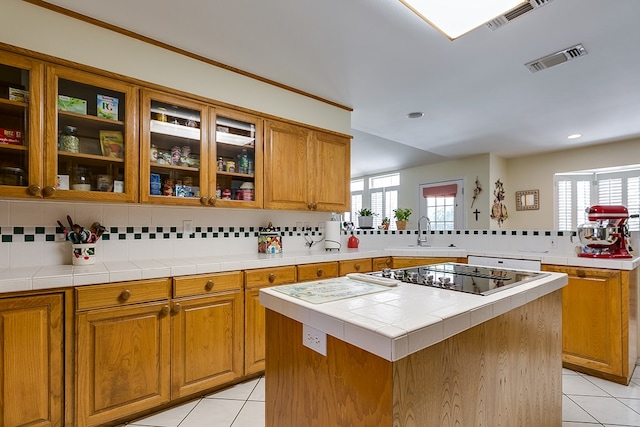 kitchen featuring backsplash, sink, tile counters, and a center island