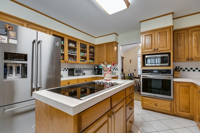 kitchen featuring light tile patterned floors, backsplash, stainless steel appliances, tile counters, and a kitchen island