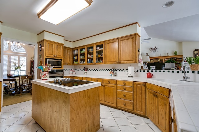 kitchen with sink, tile countertops, a center island, appliances with stainless steel finishes, and kitchen peninsula