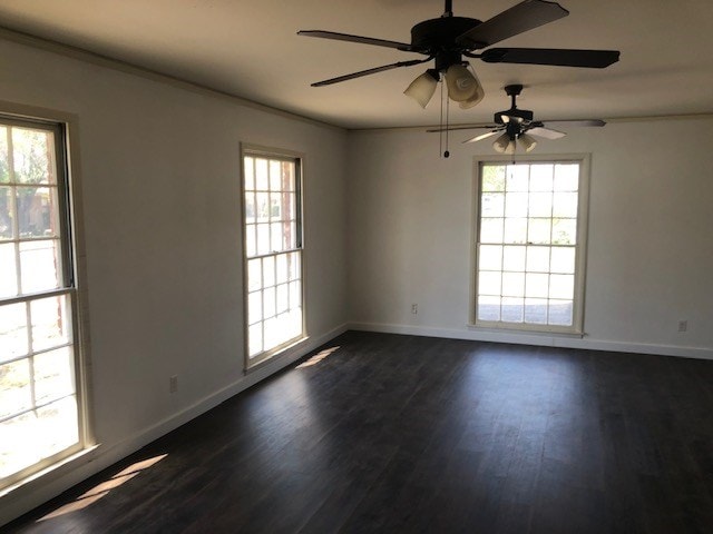 spare room with dark wood-type flooring, ceiling fan, and baseboards