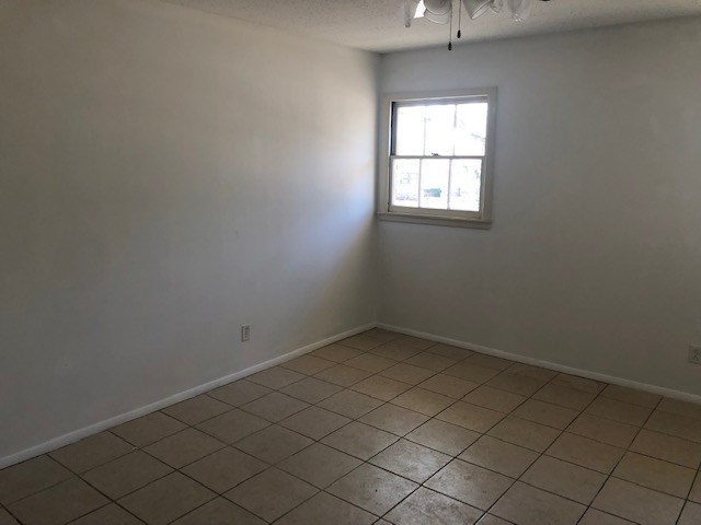spare room featuring a textured ceiling, baseboards, and ceiling fan