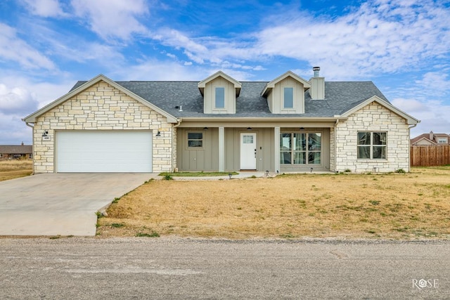 view of front of house with board and batten siding, fence, concrete driveway, a garage, and stone siding