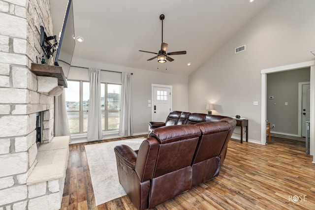 living room featuring hardwood / wood-style flooring, ceiling fan, high vaulted ceiling, and a fireplace