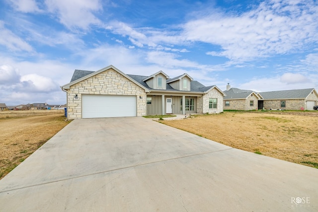 view of front facade with stone siding, driveway, an attached garage, and a front yard