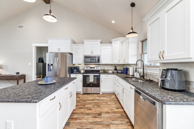 kitchen featuring white cabinetry, appliances with stainless steel finishes, decorative light fixtures, and sink