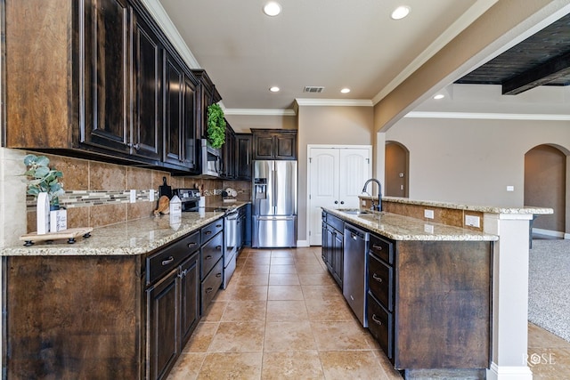 kitchen with sink, backsplash, light stone countertops, and appliances with stainless steel finishes