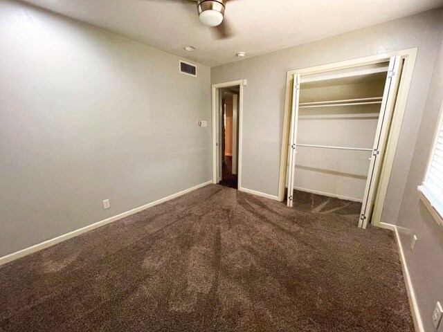 unfurnished bedroom featuring dark colored carpet, ceiling fan, and a closet