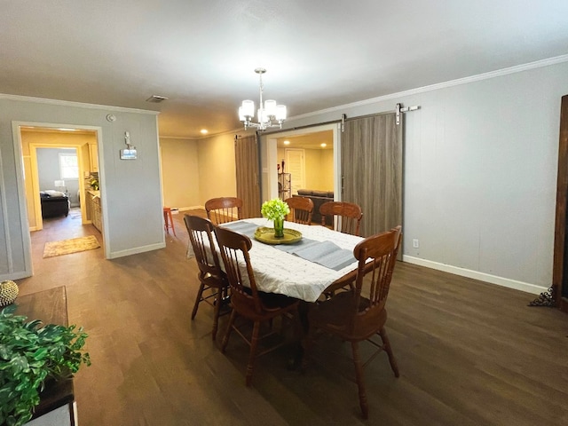 dining space with dark wood-type flooring, ornamental molding, a barn door, and a chandelier