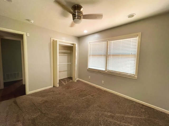 unfurnished bedroom featuring ceiling fan, dark carpet, and a closet