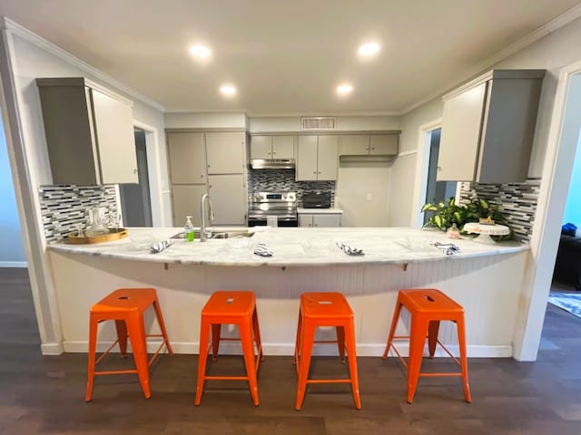 kitchen with gray cabinets, stainless steel electric stove, a breakfast bar area, ornamental molding, and kitchen peninsula