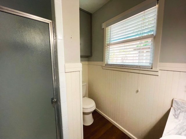 bathroom featuring hardwood / wood-style flooring, a shower with door, and toilet