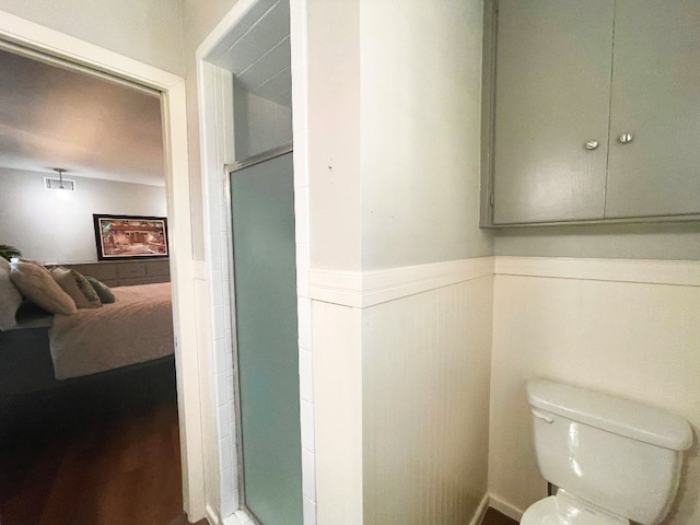 bathroom with hardwood / wood-style flooring, toilet, and walk in shower