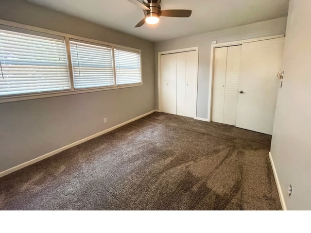 unfurnished bedroom featuring two closets, ceiling fan, and carpet