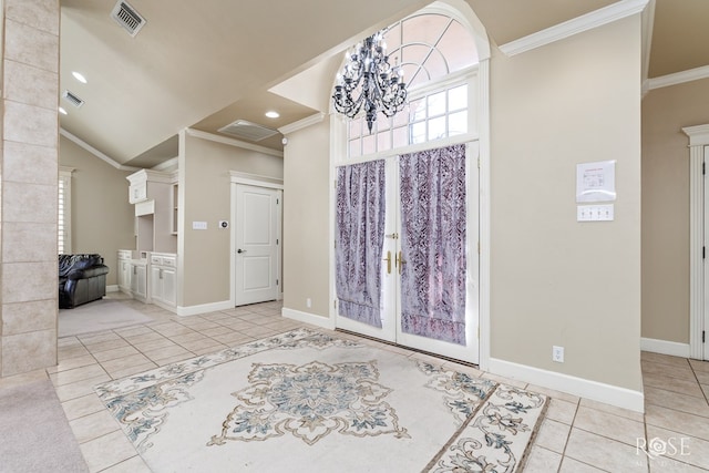 tiled entrance foyer with french doors, ornamental molding, vaulted ceiling, and an inviting chandelier