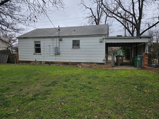 rear view of property with a lawn and a carport