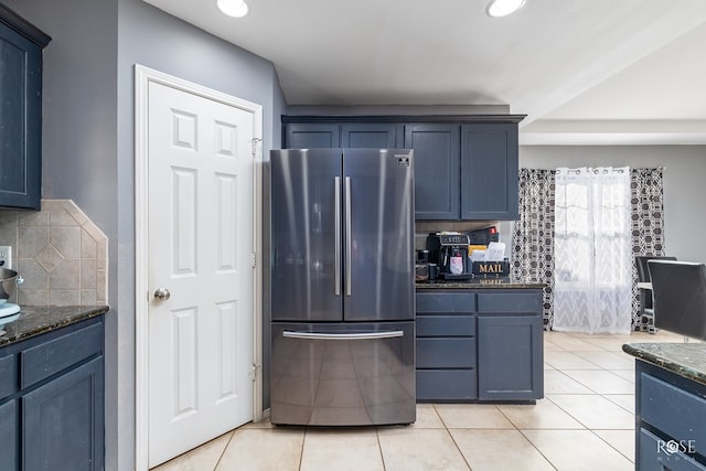 4122 Harmony Ln, San Angelo, TX 76904 - kitchen with freestanding refrigerator, dark stone countertops, tasteful backsplash, light tile patterned floors, and blue cabinetry