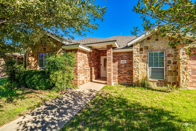 4122 Harmony Ln, San Angelo, TX 76904 - view of front of property featuring a front yard, roof with shingles, stone siding, and brick siding