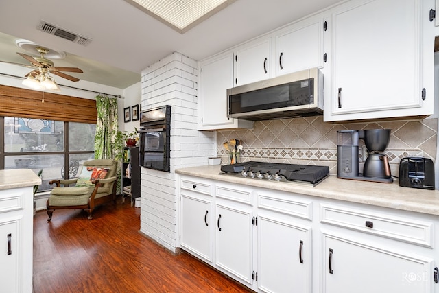 kitchen featuring appliances with stainless steel finishes, dark hardwood / wood-style floors, tasteful backsplash, white cabinetry, and ceiling fan