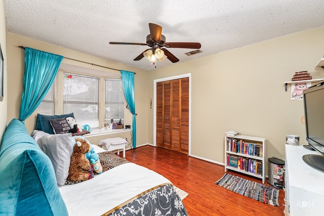 bedroom featuring hardwood / wood-style flooring, ceiling fan, a closet, and a textured ceiling