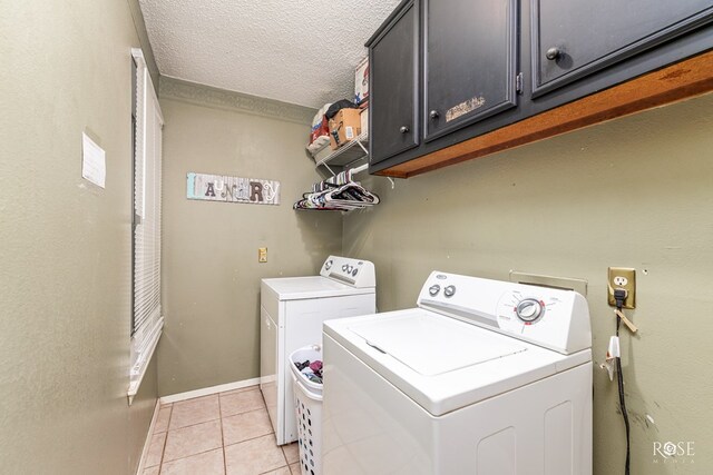 laundry area featuring cabinets, light tile patterned floors, washing machine and clothes dryer, and a textured ceiling