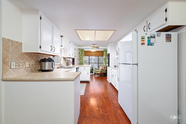 kitchen featuring sink, dark hardwood / wood-style flooring, kitchen peninsula, white fridge, and white cabinets