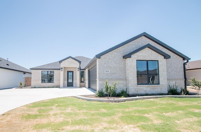 view of front of house with brick siding, a garage, stone siding, driveway, and a front lawn