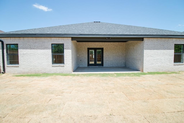 back of house featuring a shingled roof, a patio area, french doors, and brick siding