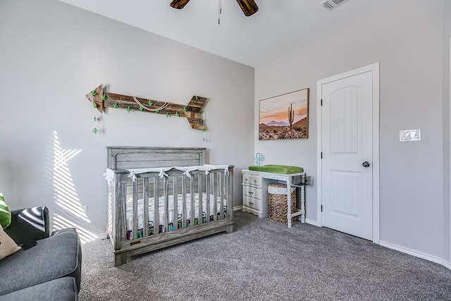 bedroom with baseboards, a crib, carpet, and a ceiling fan