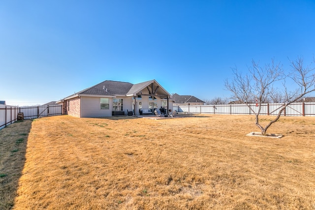 rear view of house with a fenced backyard, a patio, a shingled roof, and a yard