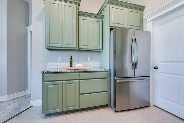 kitchen featuring light stone counters, green cabinets, and freestanding refrigerator