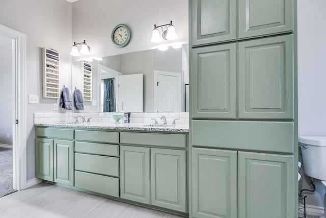 full bathroom with double vanity, toilet, baseboards, and a sink