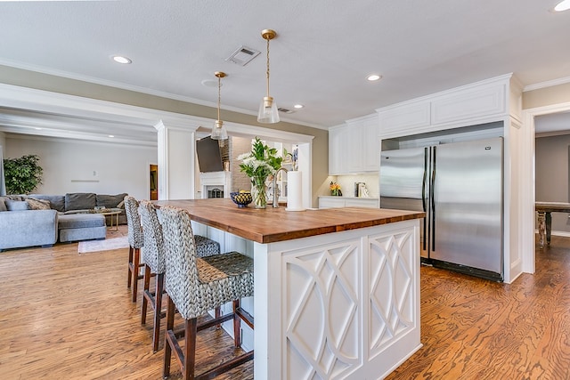 2622 Oxford Ave, San Angelo, TX 76904 - kitchen with built in fridge, wooden counters, wood finished floors, white cabinetry, and recessed lighting