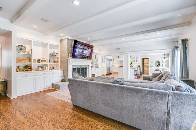 2622 Oxford Ave, San Angelo, TX 76904 - living room featuring beamed ceiling, light wood-style floors, a fireplace with raised hearth, decorative columns, and recessed lighting