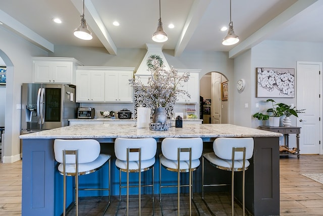 kitchen with beamed ceiling, stainless steel fridge with ice dispenser, pendant lighting, a large island, and white cabinets