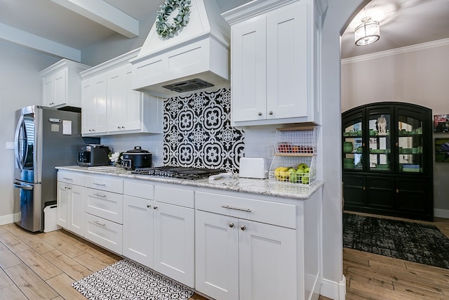 kitchen with premium range hood, white cabinetry, backsplash, stainless steel appliances, and light wood-type flooring