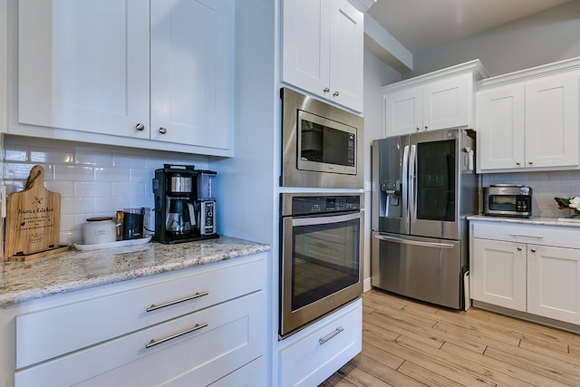 kitchen featuring stainless steel appliances, white cabinets, and decorative backsplash