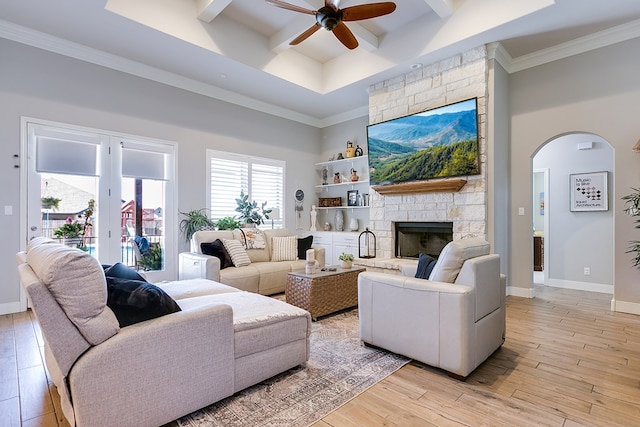 living room with a stone fireplace, light hardwood / wood-style floors, and a high ceiling