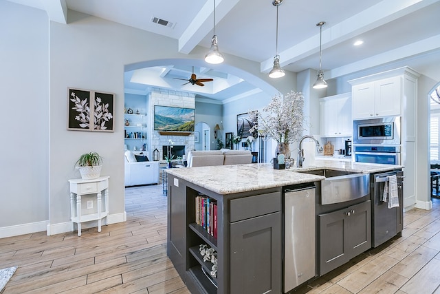 kitchen featuring hanging light fixtures, an island with sink, ceiling fan, beam ceiling, and white cabinets