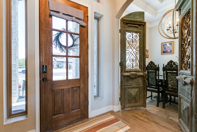 foyer entrance featuring an inviting chandelier, ornamental molding, and light hardwood / wood-style floors