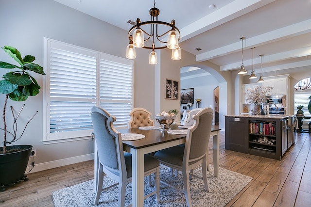 dining room with an inviting chandelier, beam ceiling, and light hardwood / wood-style floors