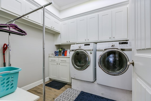 laundry area with cabinets, light hardwood / wood-style floors, and washing machine and dryer