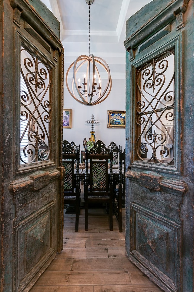 foyer entrance with wood-type flooring, ornamental molding, and an inviting chandelier